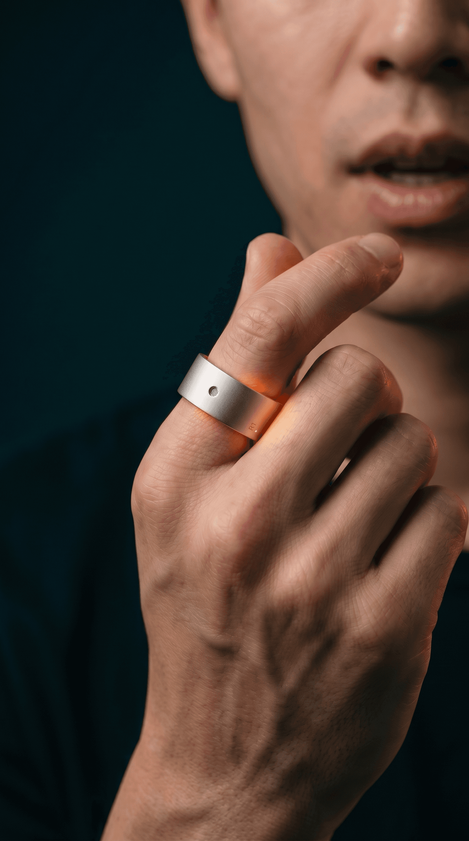 A hand raised near the mouth, speaking into the microphone on the Rhyme Devices R1 ring