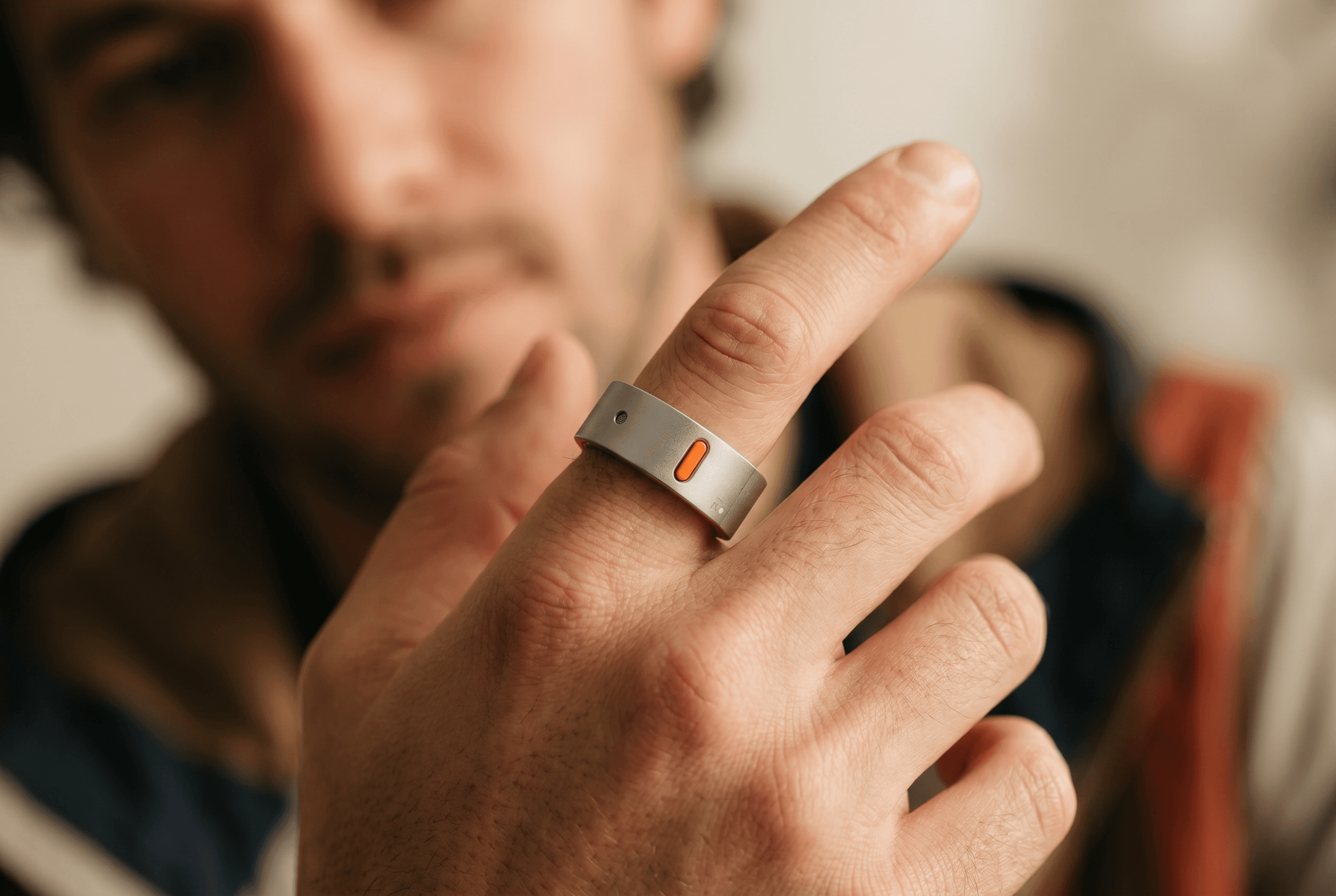 A person holding up their index finger wearing the Rhyme Devices R1 ring, their face soft in the background